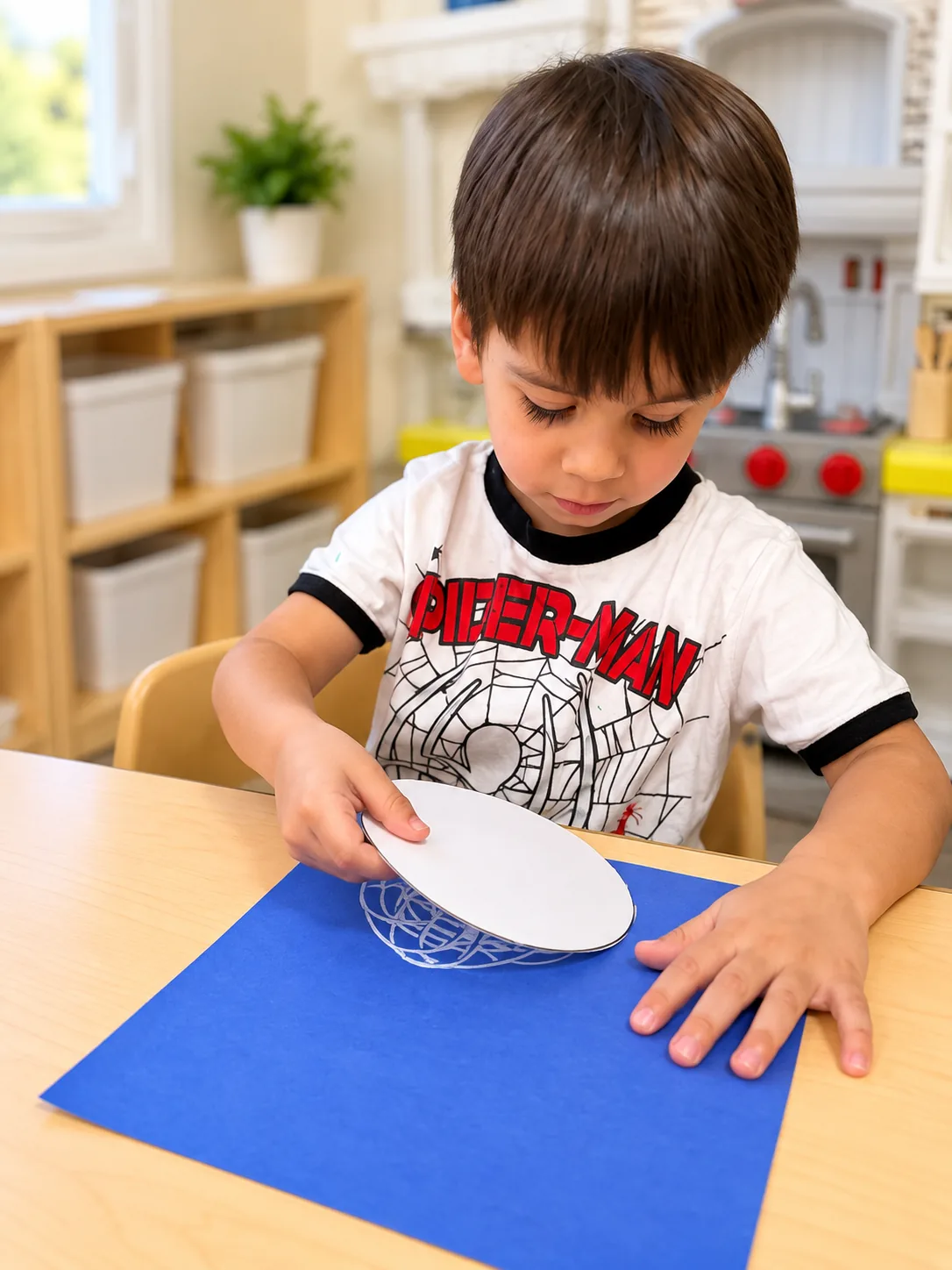 Young boy assembling a paper plate craft on blue construction paper