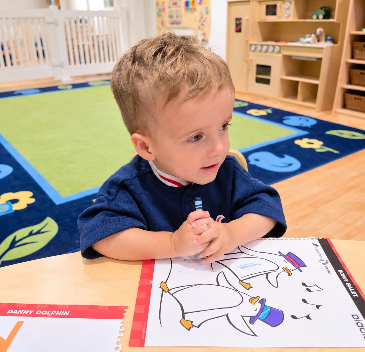Child coloring a picture at a small classroom table with learning materials nearby