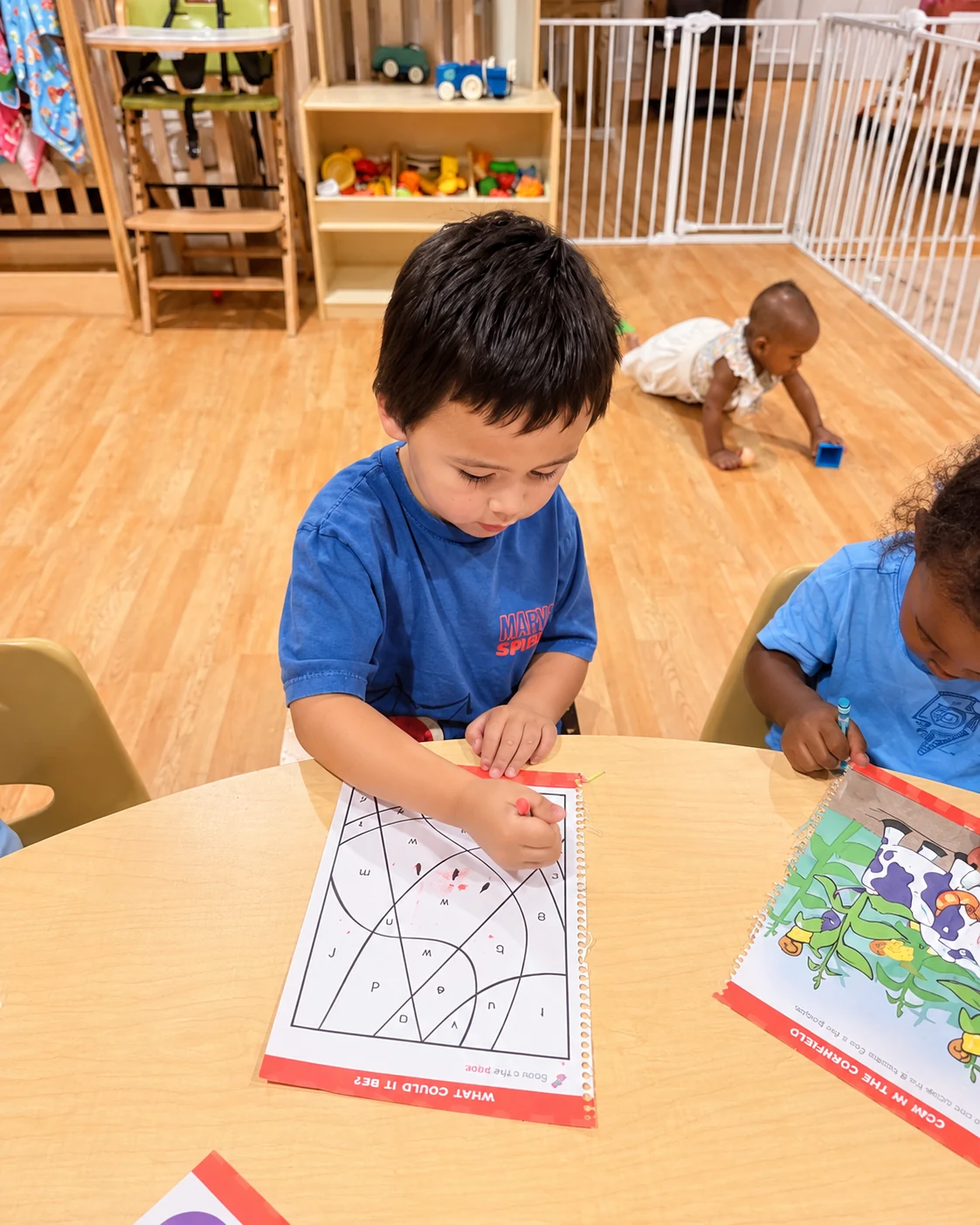 Children drawing together at a classroom table surrounded by learning materials