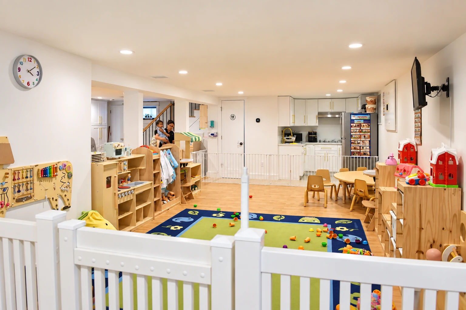 Bright open play and learning space with wooden toys, activity rug, child-sized furniture and kitchen area