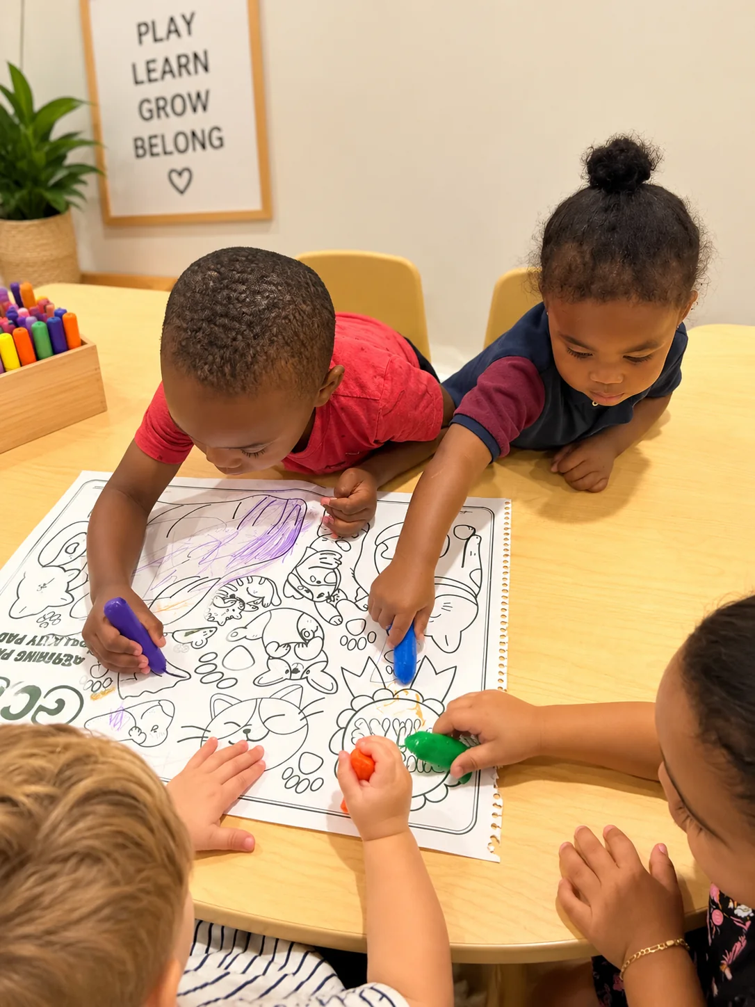 Four young children sharing crayons while coloring a classroom activity page