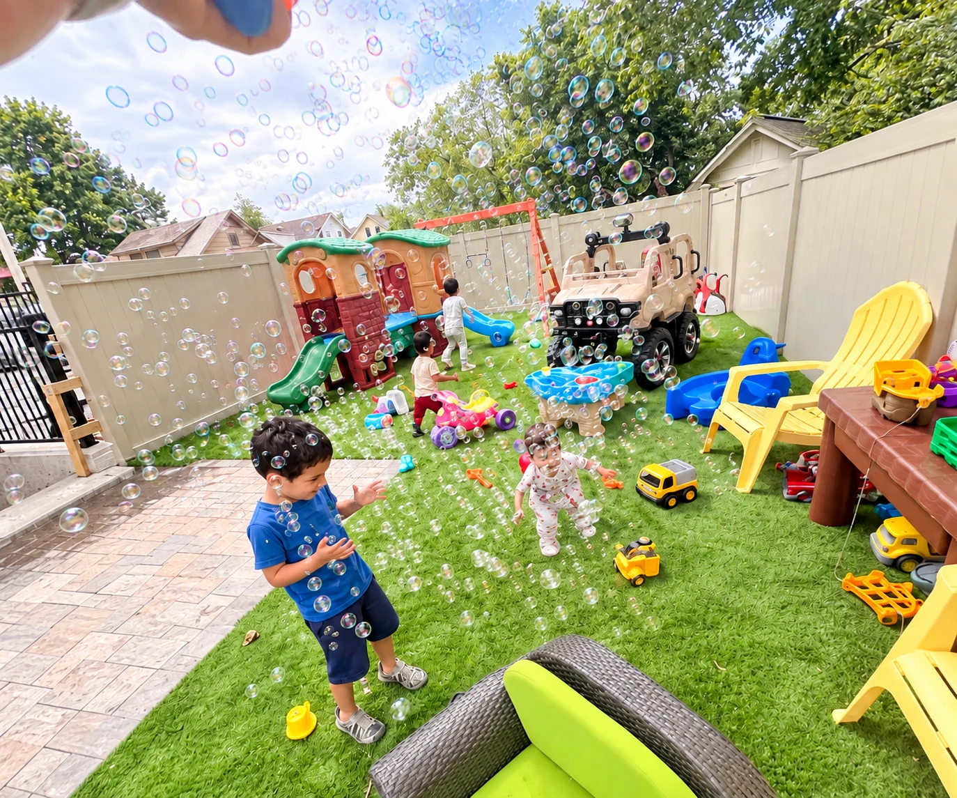 Children chasing bubbles and playing together in the fenced backyard