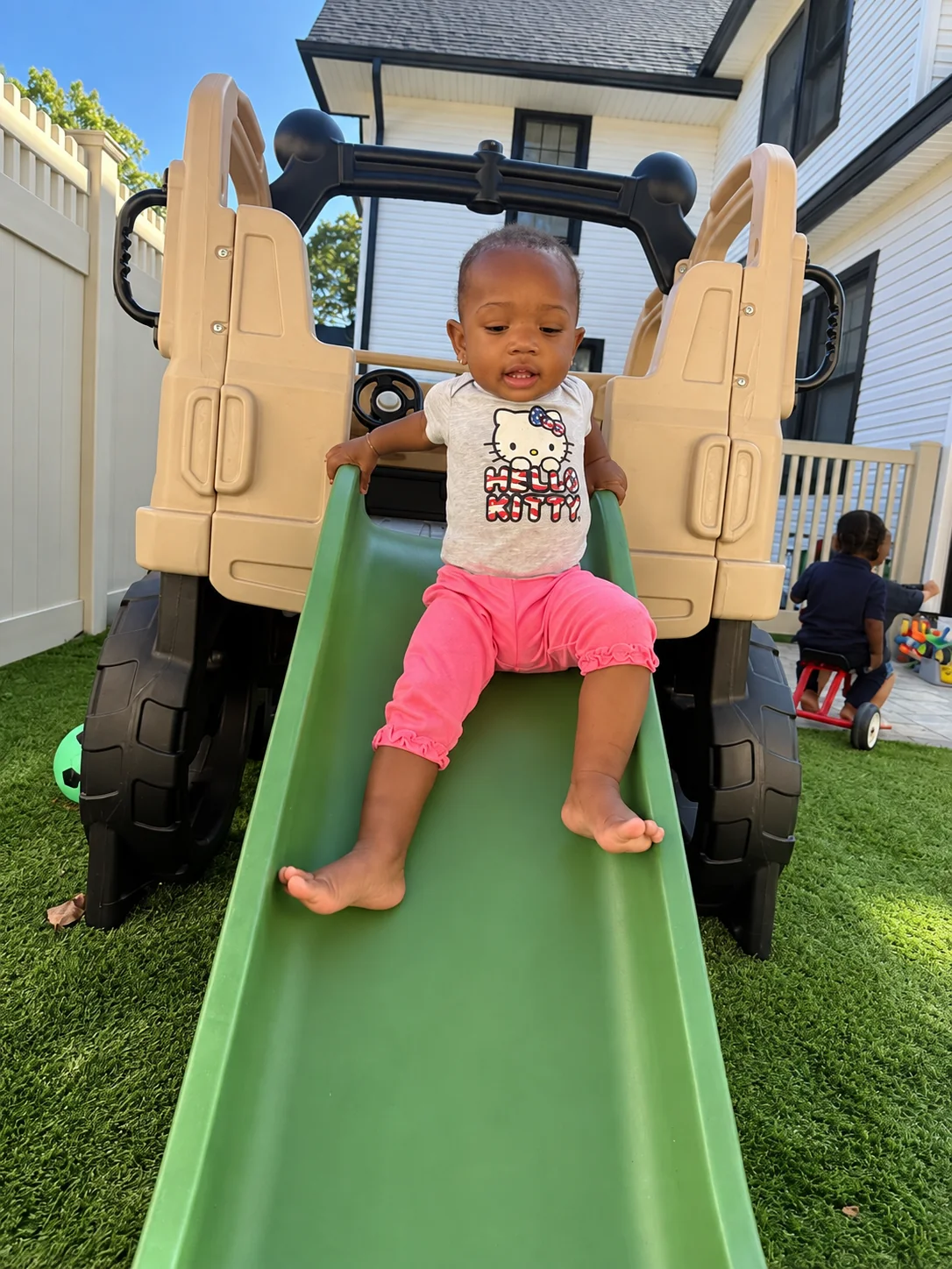 Toddler sliding down the green slide of an outdoor play truck