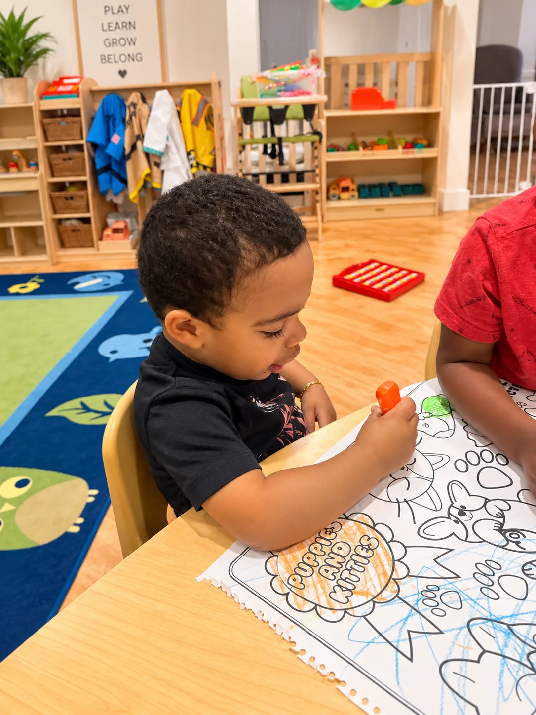 Young child carefully coloring an animal activity page in the classroom