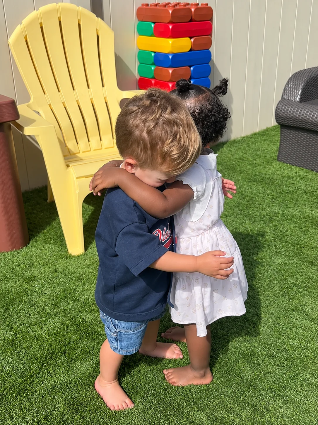 Two toddlers hugging during outdoor play