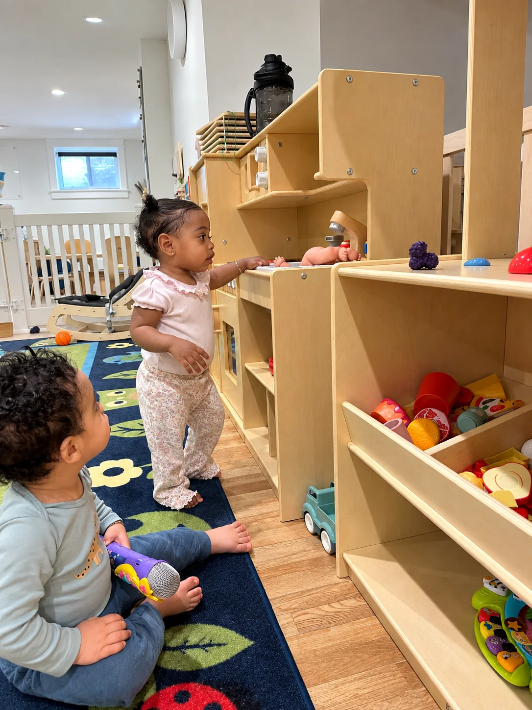 Young children exploring pretend kitchen toys in the playroom