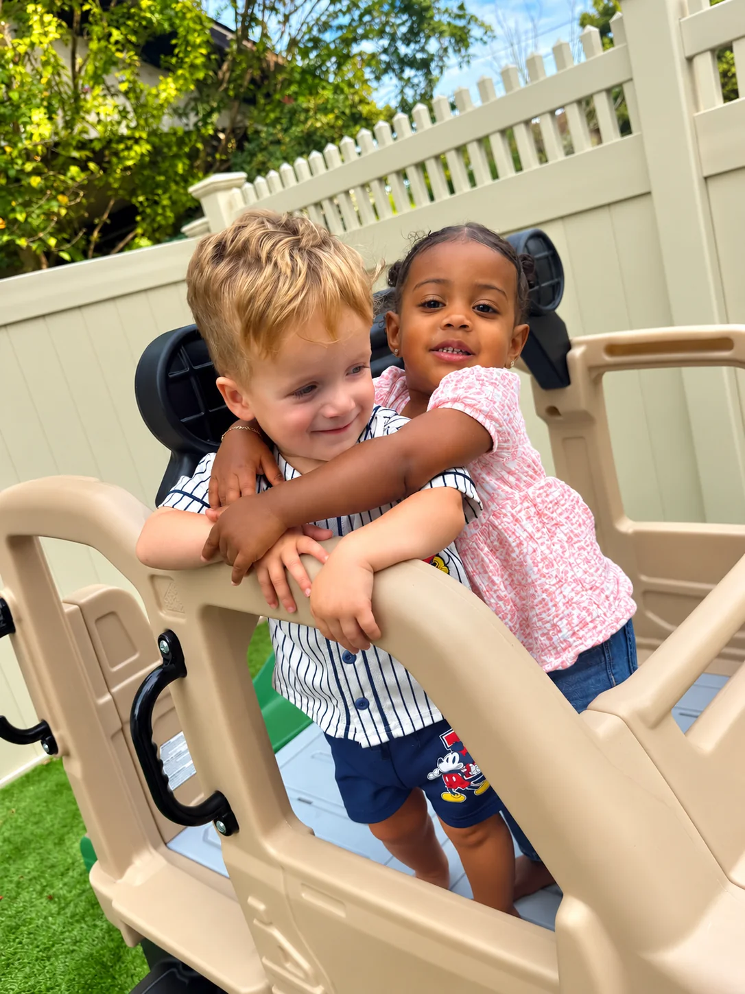 Two toddlers sharing a hug on an outdoor play structure