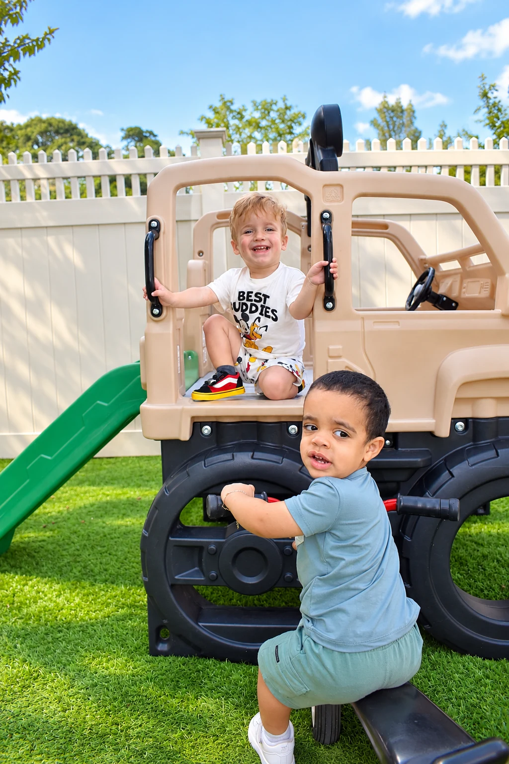 Children climbing and smiling on a ride-on playground vehicle in the sunny backyard