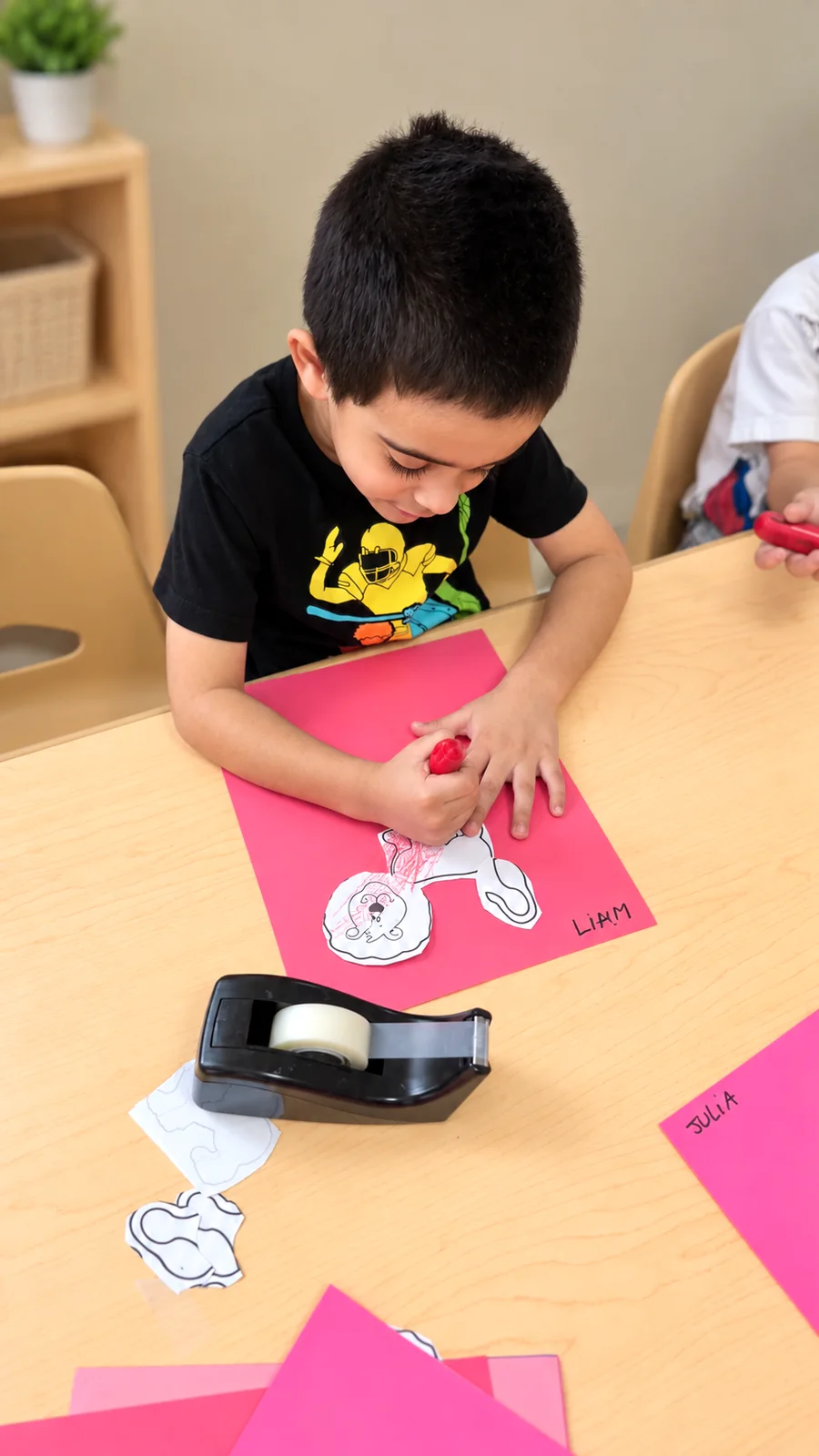 Preschool child coloring a paper figure during a creative table activity
