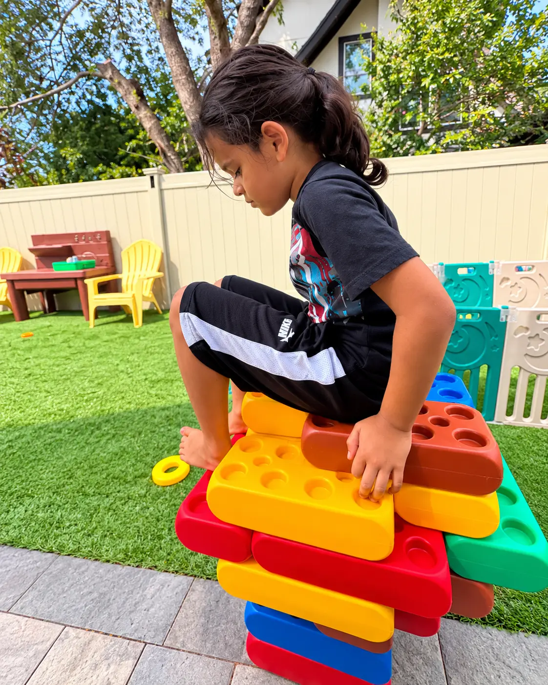 Child stacking giant colorful building blocks during outdoor play