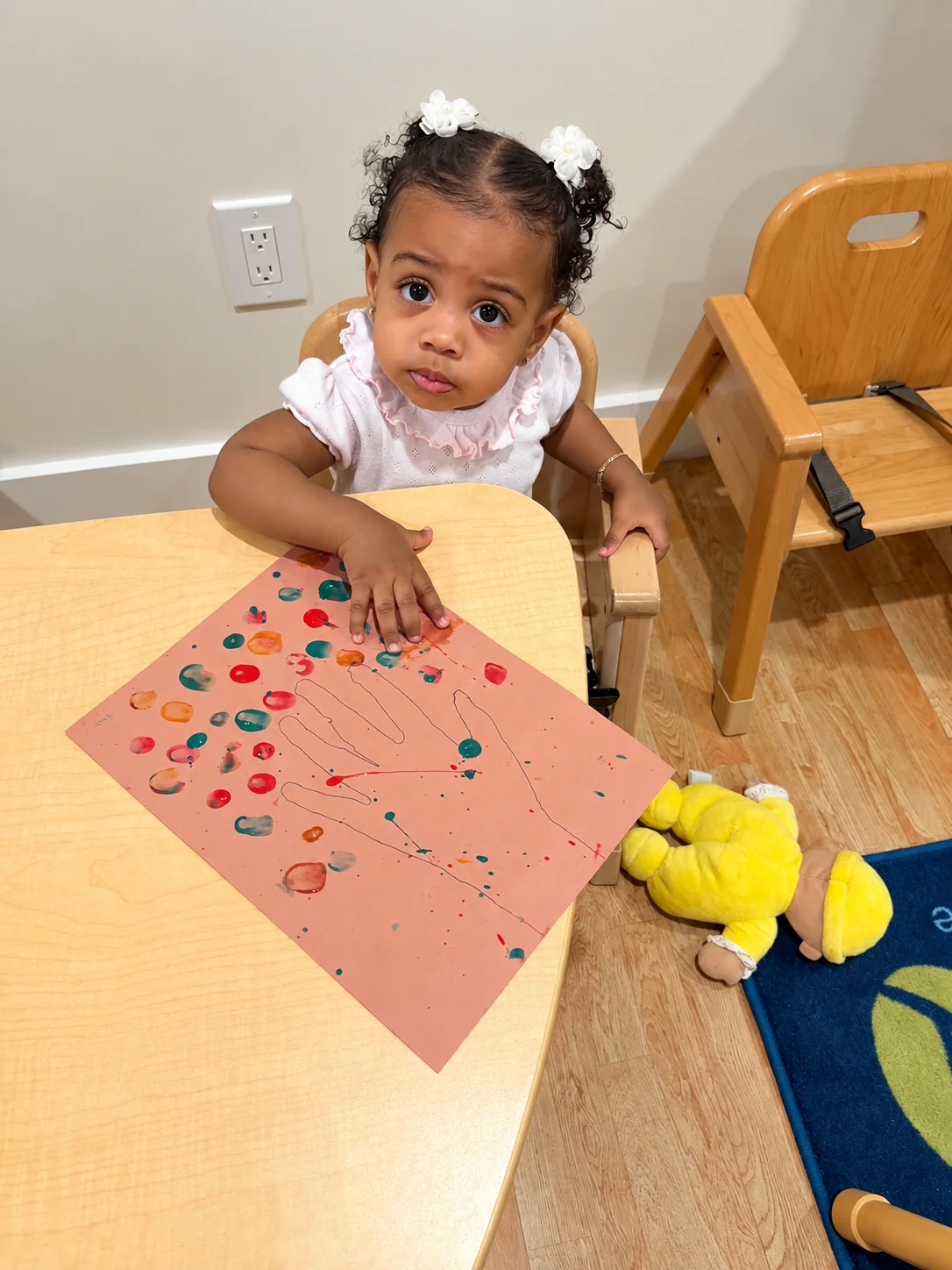 Toddler creating a colorful fingerprint painting at the activity table