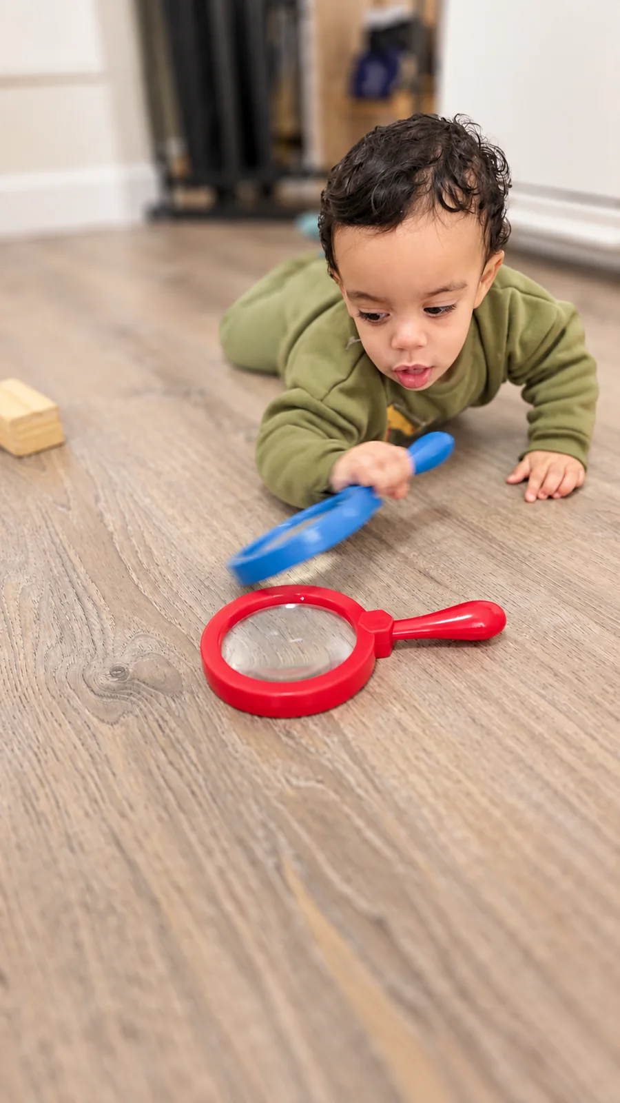 Toddler exploring magnifying glasses during floor play