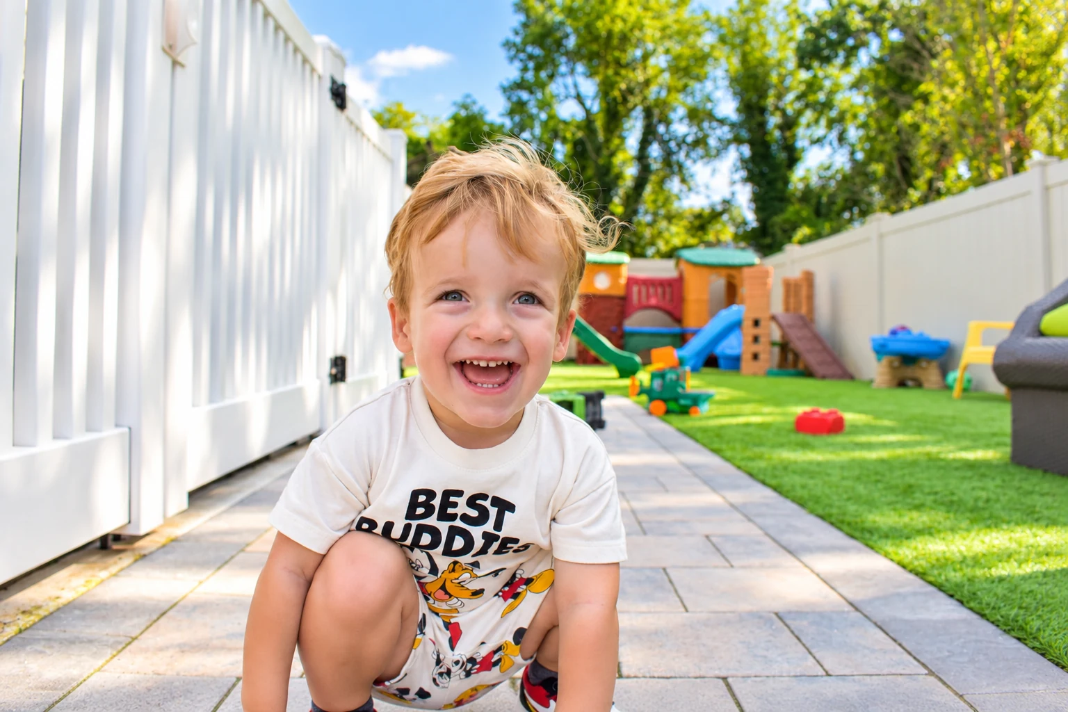 Child enjoying the spacious fenced backyard surrounded by slides and play structures
