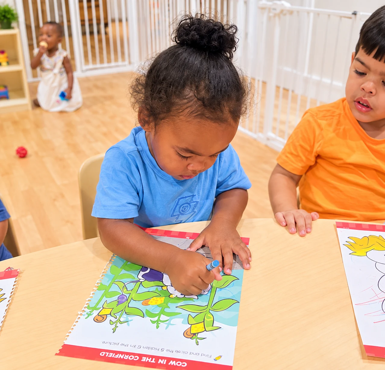 Children coloring together at a classroom table with crayons and activity sheets