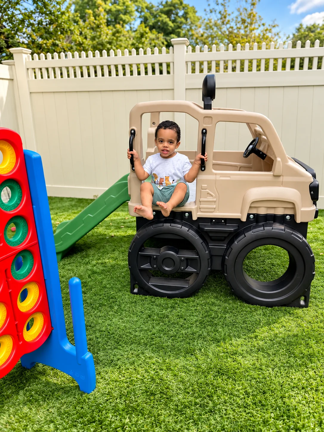 Toddler sitting in a play truck beside an outdoor slide