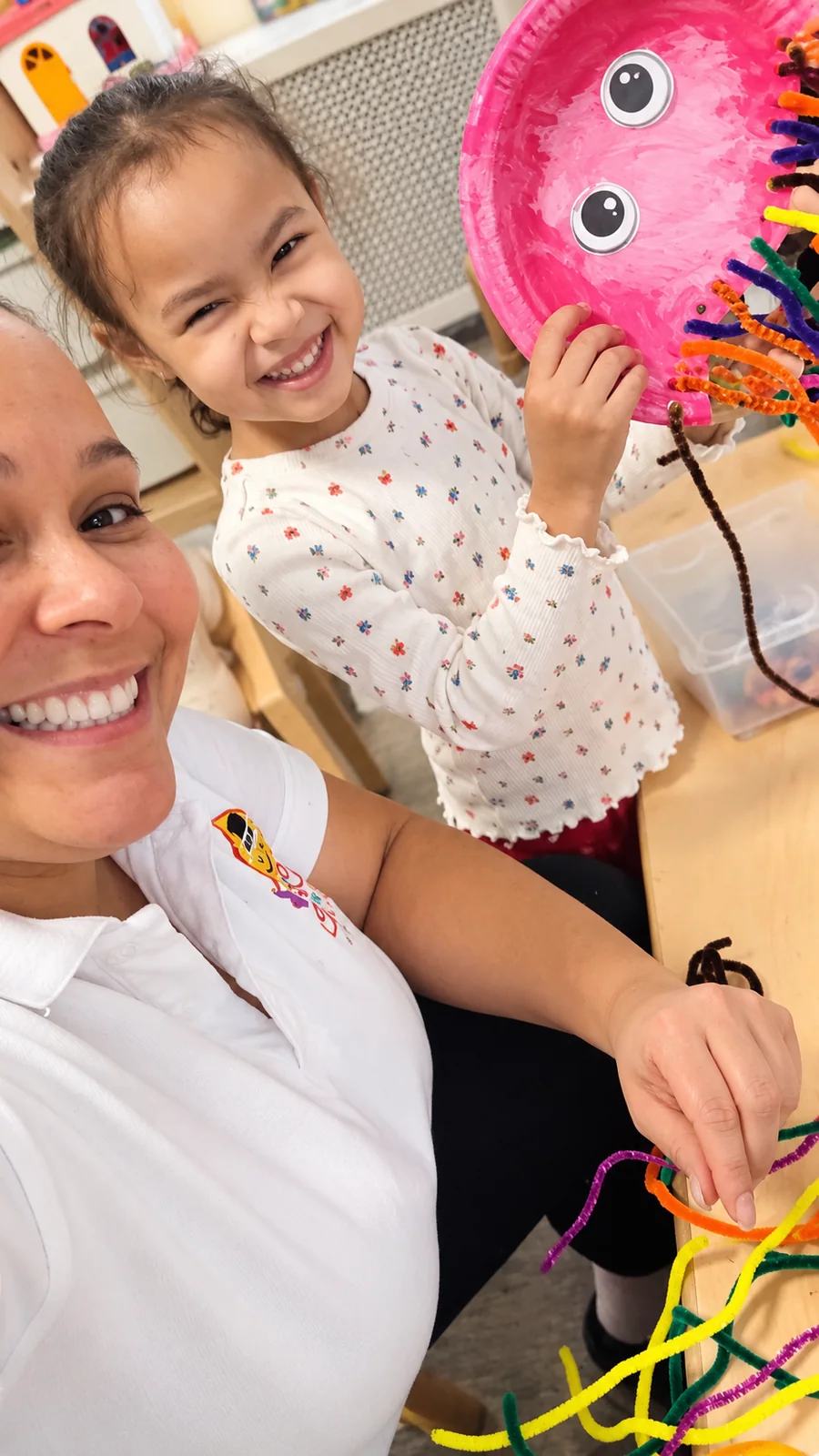 Child proudly sharing a colorful octopus craft with her teacher