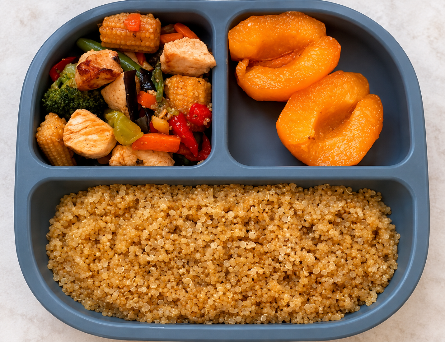 Chicken and quinoa with mixed vegetables and peaches served in a divided meal tray