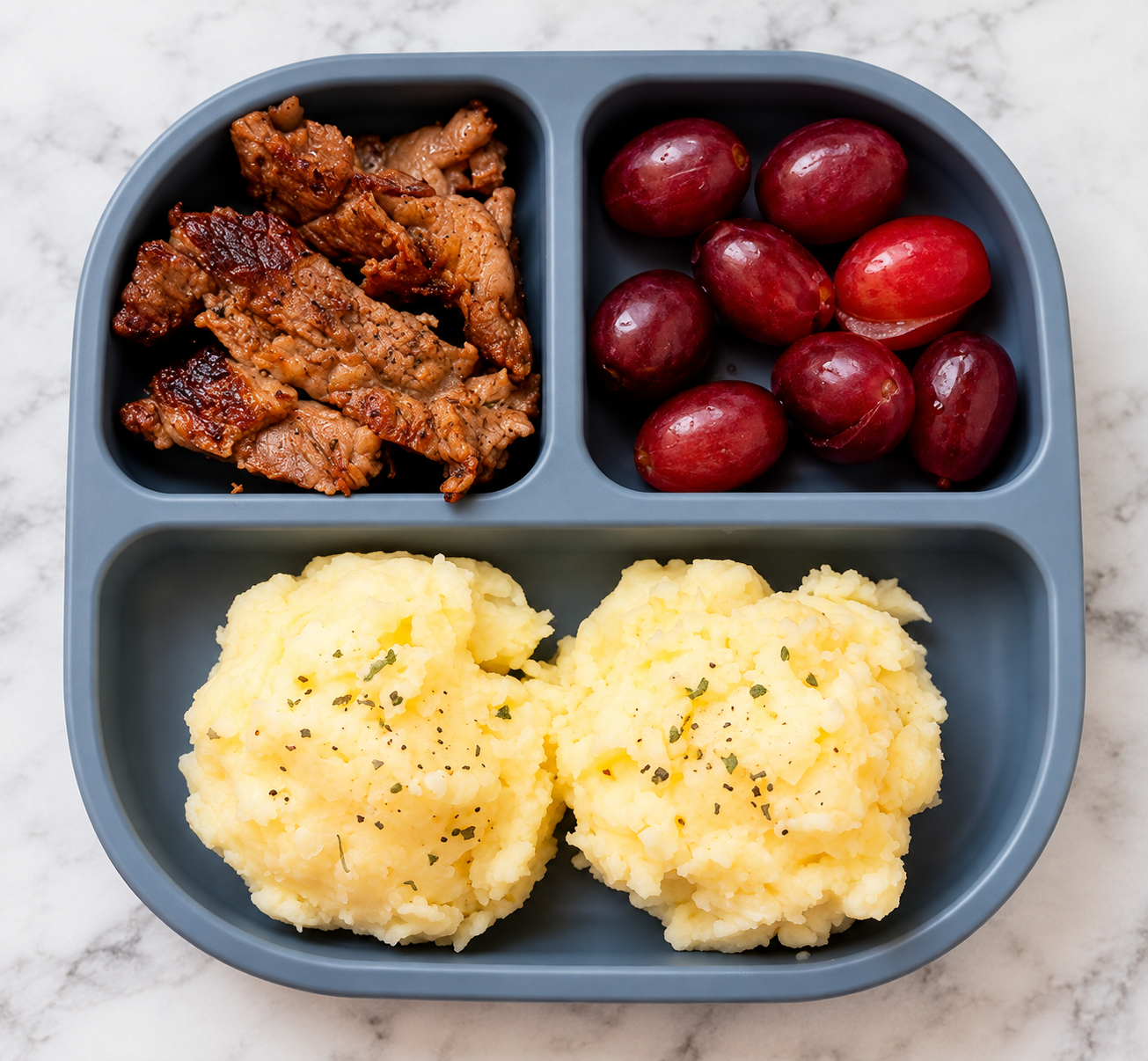 Chicken, grapes, and mashed potatoes served in a divided meal tray