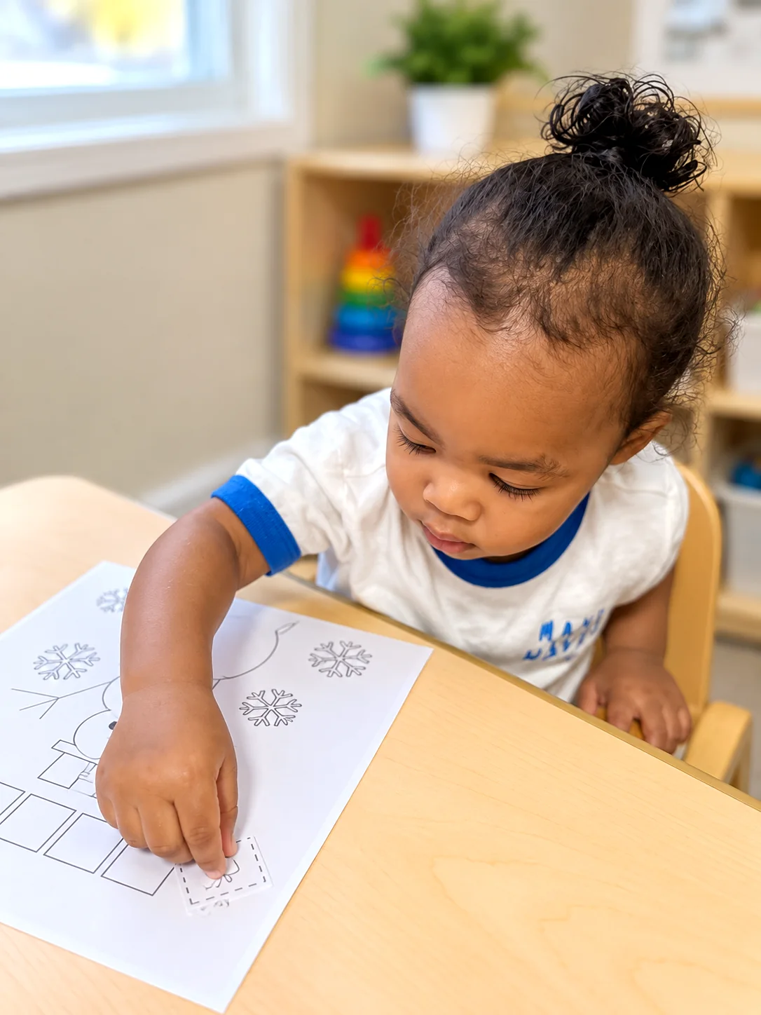Young child practicing fine motor skills with a seasonal cut-and-paste worksheet