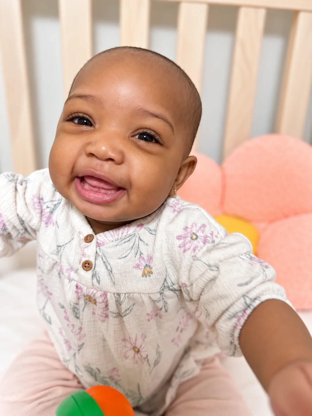 Smiling infant playing with a colorful ball in a cozy indoor space