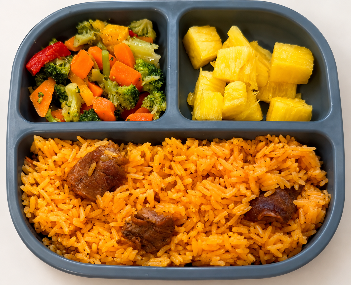 Beef and rice with mixed vegetables and pineapple served in a divided meal tray