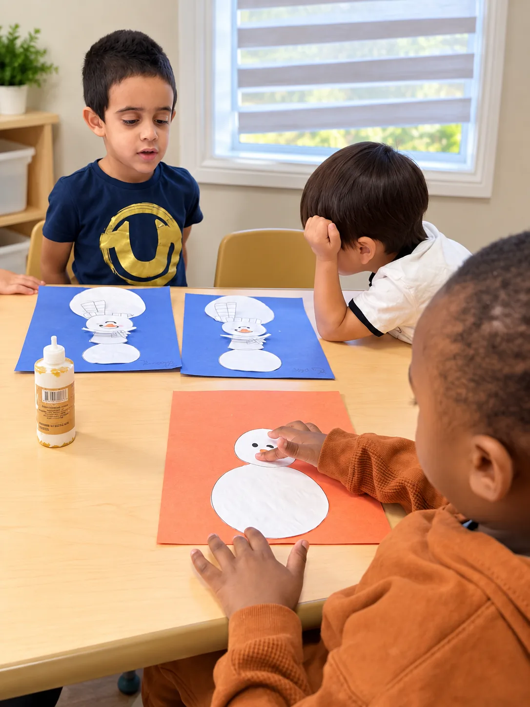 Three children working side by side on snowman paper crafts at a classroom table