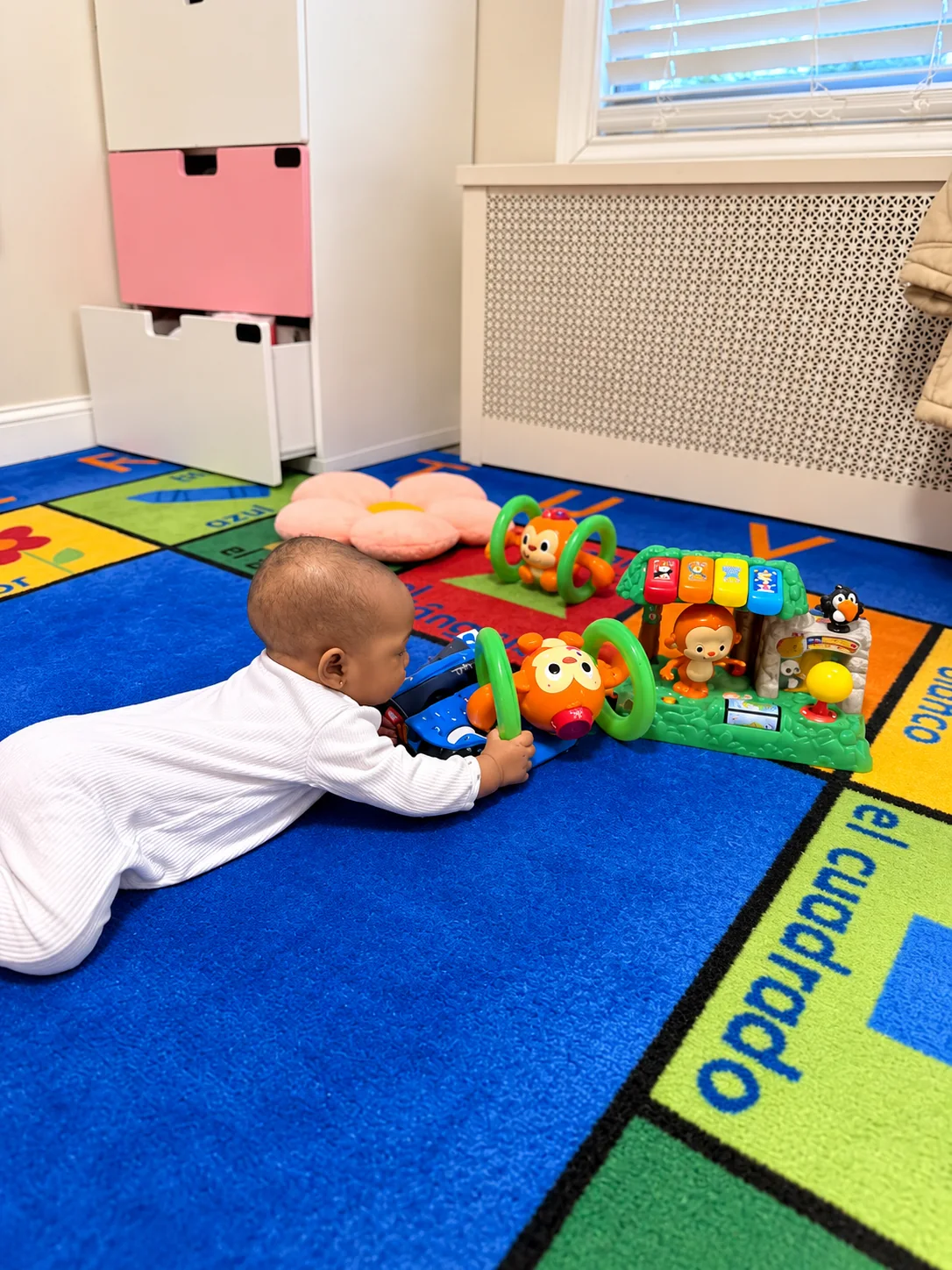 Infant reaching for a colorful activity toy in the classroom play area