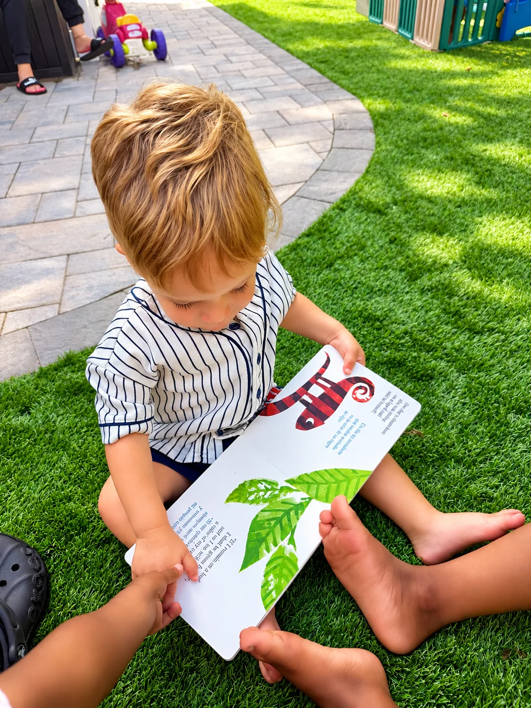 Children exploring illustrated pages together while seated on the grass