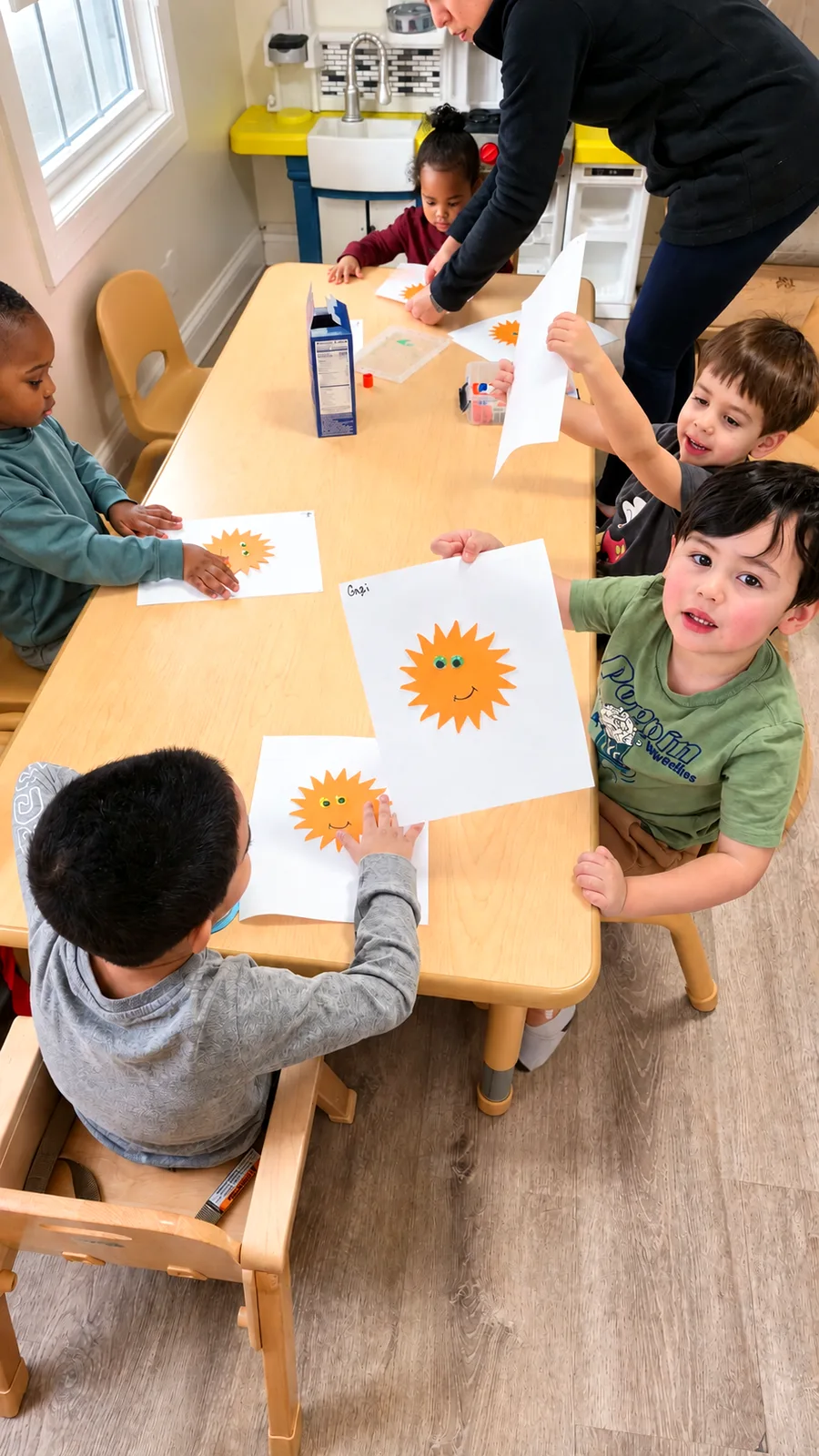 Children proudly showing their sunshine paper crafts at a classroom table with a teacher