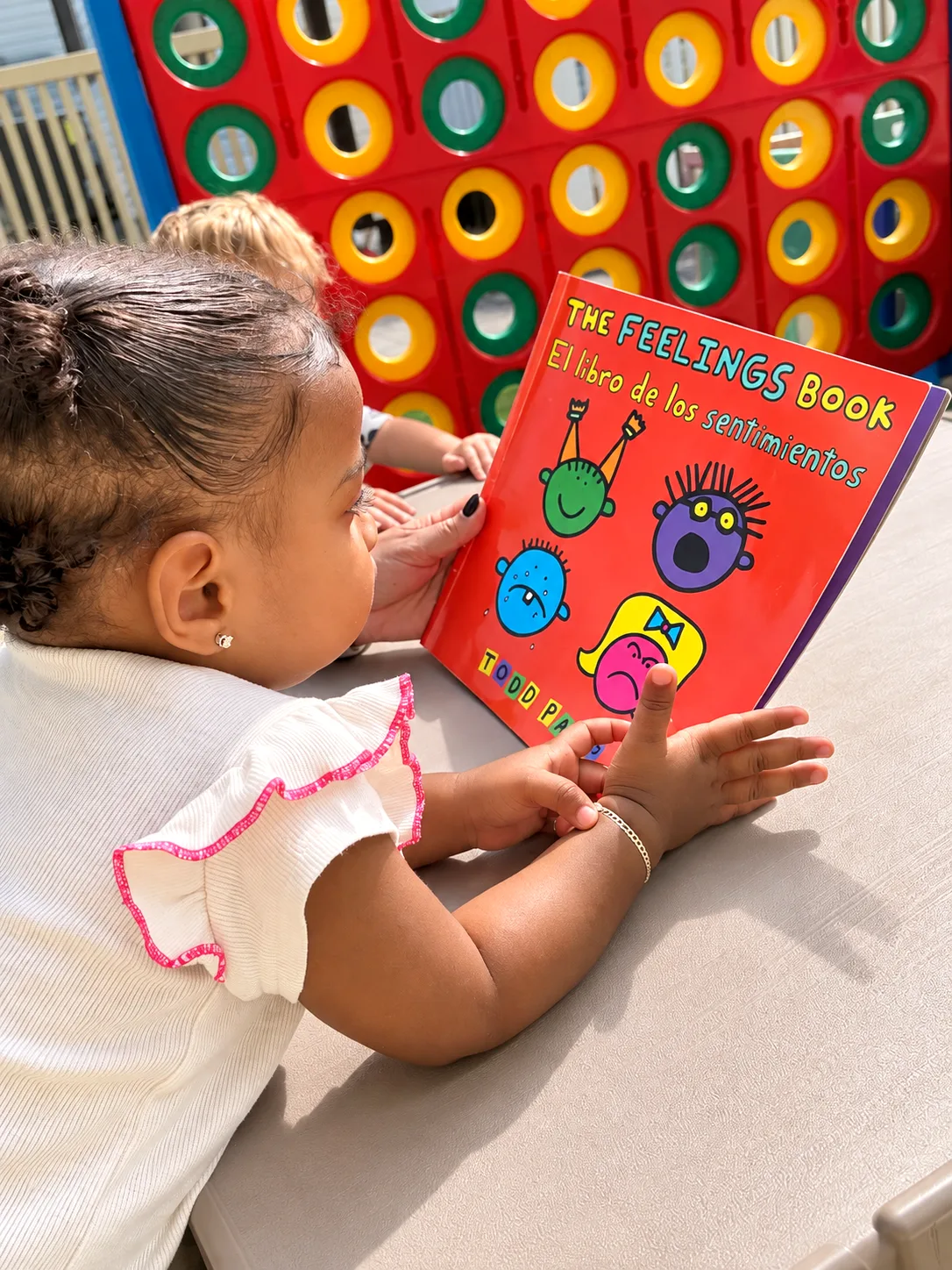 Toddler pointing at a bilingual picture book about feelings during story time