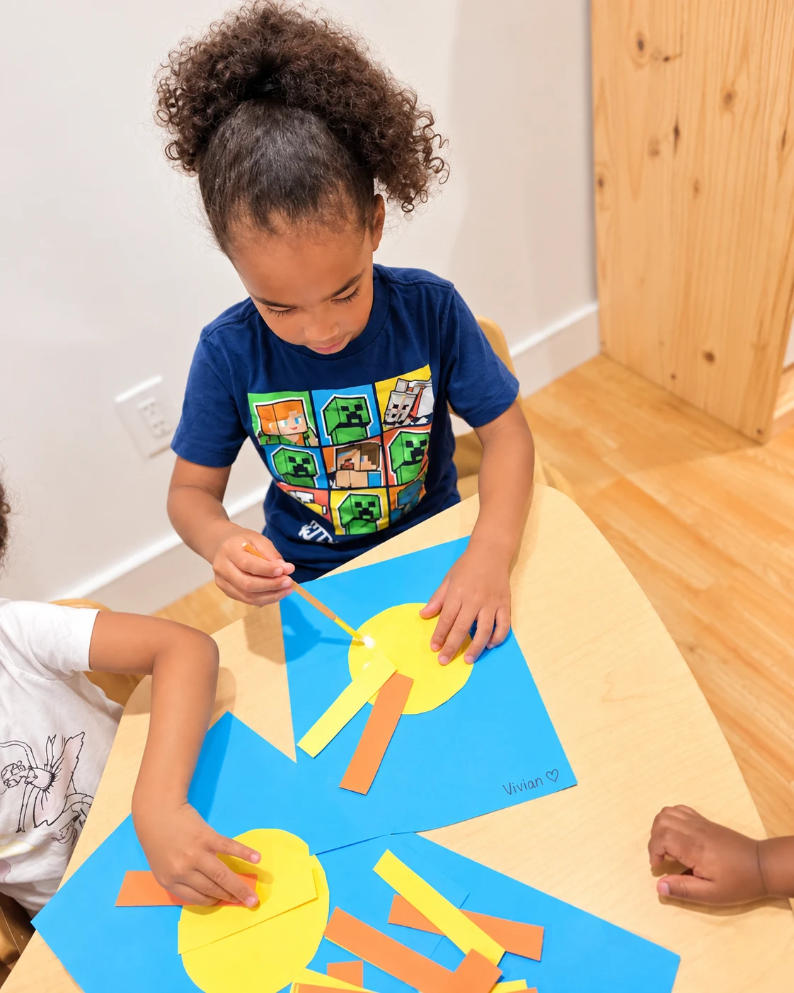 Child gluing paper shapes to create a colorful craft project